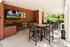 Inviting outdoor lounge area with modern seating, brick accent wall, wall-mounted TV, and lush greenery views, perfect for entertainment and relaxation.