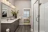 Elegant bathroom with modern fixtures, glass shower, and double vanity leads to a cozy bedroom. Stylish and inviting space for relaxation.