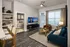 Modern living room with stylish decor, featuring a cozy seating area, flat screen TV, and large window for natural light. Open access to a comfortable bedroom.