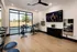 Sleek and modern fitness room with a wall-mounted TV, spin bikes, and yoga mats, flooded with natural light from large windows.