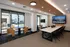 Modern communal space with sleek conference table, cozy seating, large windows for natural light, and a wall-mounted TV.