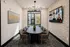 Modern conference room featuring a sleek oval table, stylish chairs, artistic decor, and a large screen showcasing a virtual meeting.
