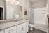 Elegant bathroom with granite countertop, sleek under-sink storage, and a chic shower curtain, offering a modern touch.