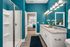 Elegant bathroom with teal walls, featuring a granite countertop vanity, modern lighting, and a glass-enclosed shower, leading to a cozy bedroom.