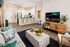 Modern open-concept living room with a stylish kitchen, featuring sleek barstools and state-of-the-art appliances. The cozy lounge area includes a plush sofa, trendy décor, and a chic wooden entertainment console.