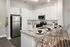 Modern kitchen with sleek white cabinetry, stainless steel appliances, and a stylish breakfast bar with clear stools.