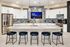 Elegant modern kitchen with a spacious island, stylish pendant lighting, and sleek stainless-steel appliances. Featuring eye-catching backsplash and comfortable bar seating, perfect for entertaining.