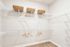 Spacious walk-in closet featuring sleek white shelving, wicker baskets, and ample space for organized storage.