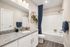 Elegant bathroom featuring a granite countertop, large mirror, and chic geometric wall shelving.