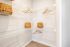 Elegant walk-in closet featuring organized wire shelving and stylish woven baskets, offering ample storage space.