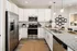 Modern kitchen featuring sleek stainless steel appliances, granite countertops, and elegant white cabinetry, illuminated by stylish pendant lighting.