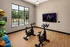 Modern exercise room featuring two high-tech stationary bikes, wall-mounted TV, and large window with serene outdoor view.