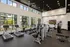 Modern fitness center with state-of-the-art equipment, large windows providing natural light, and a view of the pool area outside.