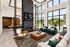 Luxurious modern living room with soaring ceilings, large windows, sleek fireplace, and stylish seating, offering a bright and inviting ambiance.