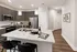 Modern kitchen with sleek dark cabinetry, marble countertops, and stainless steel appliances, featuring an inviting breakfast bar with elegant pendant lighting.