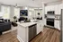 Modern open-concept living space featuring a sleek kitchen with stainless steel appliances, an elegant island, and a cozy living room with large windows.