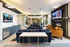Luxurious open-concept lounge featuring plush navy sofas, modern leather armchairs, a sleek fireplace, and dual wall-mounted TVs, perfect for relaxing and entertaining.