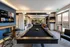 Bright and modern recreational room featuring a sleek pool table, comfortable seating, and dual wall-mounted TVs, perfect for entertainment and relaxation.