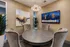 Elegant meeting room featuring a round table with plush chairs, modern art, and a large TV mounted on the wall.