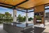 Luxurious rooftop terrace with modern outdoor kitchen, stylish seating, and stunning views of greenery under a wooden ceiling.