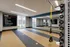 Modern fitness room featuring mirrored walls, workout equipment, and a motivational CrossFit schedule on display.