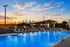 Luxurious rooftop pool with loungers overlooking a vibrant city skyline at sunset, perfect for relaxation and enjoying breathtaking views.