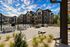 Modern apartment complex with spacious courtyard and stunning blue sky, featuring comfortable seating, entertainment area, and lush greenery.