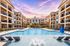 Luxurious apartment complex with stunning pool, modern balconies, and vibrant sunset backdrop.