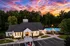 Charming clubhouse with elegant architecture surrounded by lush greenery at sunset, featuring a serene outdoor pool area and vibrant landscaping.