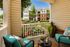 Charming apartment balcony with comfortable seating, a lush garden view, and vibrant plant decor, perfect for relaxation.