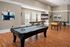 Luxurious entertainment room with a stylish pool table, foosball, and comfortable seating, enhanced by modern decor and vibrant art.