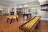 Vibrant recreational room featuring a foosball table, pool table, and shuffleboard in a stylish open space with hardwood floors.