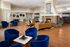Elegant open lounge with plush blue chairs, cozy sofas, and a warm stone fireplace creating an inviting atmosphere.