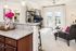 Chic apartment interior with sleek granite kitchen island, vibrant decor, and spacious living area leading to sunlit balcony.