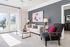 Bright and inviting living room with elegant gray accent wall, plush furnishings, and contemporary artwork, bathed in natural light from glass doors leading to a scenic view.