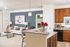 Elegant living area with modern decor, featuring a cozy sofa, stylish lighting, and a sleek granite kitchen counter with vibrant red flowers.