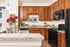 Elegant kitchen with warm wooden cabinets, granite countertops, and modern appliances. Vibrant flowers add a touch of color to the sophisticated design.