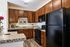 Modern kitchen with elegant wooden cabinetry, sleek black appliances, and granite countertops, accented by vibrant decor.