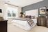 Inviting bedroom featuring a plush bed with plaid bedding, elegant lamps, and natural light streaming through large windows.
