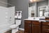Modern bathroom featuring elegant gray walls, a sleek white bathtub, and a vanity with rich wooden cabinets and stylish decor.