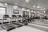 Modern fitness center with state-of-the-art treadmills, exercise bikes, and a strength training area, featuring sleek decor and bright lighting.