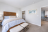 Inviting bedroom with elegant wood accents, plush bedding, and a walk-in closet, leading into a bright open living area.