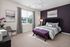 Elegant bedroom with plush bedding, rich purple accent wall, and modern decor for a cozy retreat.