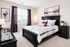 Elegant bedroom with modern black furniture, soft purple accents, and large windows for ample natural light.