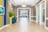 Inviting apartment hallway with elegant tile flooring, chic decor, and natural light streaming through glass doors.