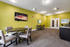 Modern community room with vibrant green walls, cozy seating, and a flat-screen TV for entertainment.