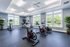 Bright and spacious fitness center with modern exercise bikes and large windows offering lush garden views.