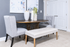 Elegant dining area with a modern round table, stylish gray chairs, and artistic decor on a plush carpet.