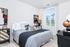 Elegant bedroom with chic decor, large window, and plush bedding, offering a cozy and stylish retreat.