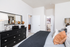 Chic bedroom with modern decor, featuring a stylish dresser, cozy textiles, and elegant lighting.